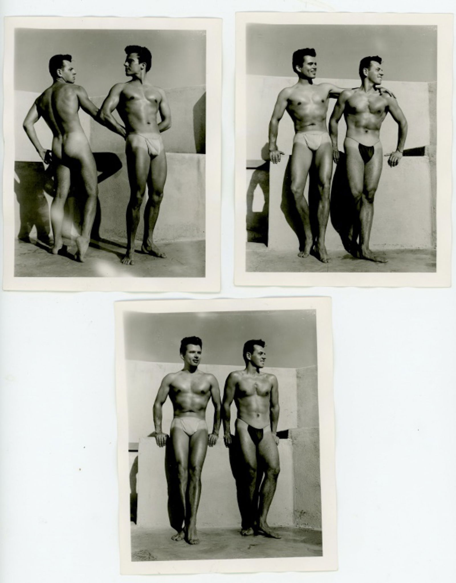 Vintage Bob Mizer AMG Male Physique Photographs: Three semigloss 4" x 5" photographs of two male models wearing posing straps on the AMG studio rooftop. Pencil numbered 14, 23 and 28 to the backs; one dated July 1956. Good condition. From the estate