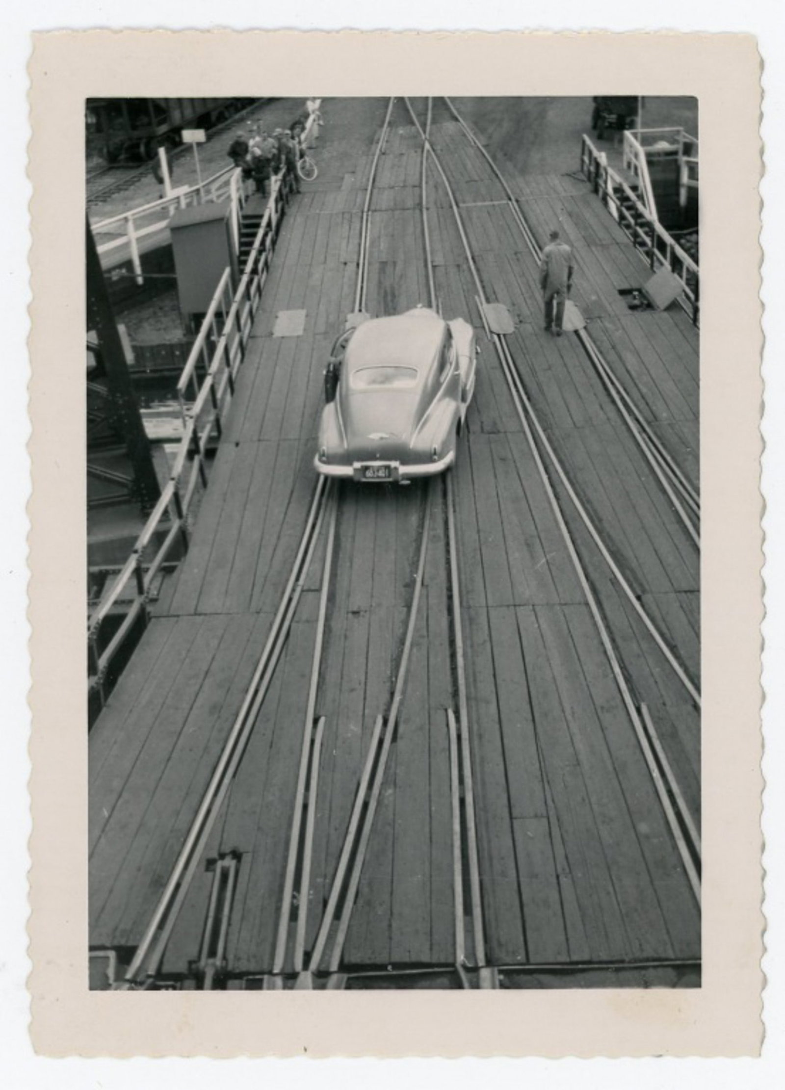 1940's Snapshot Aerial Photo of a Vintage Car on Train Tracks: Snapshot Aerial Photo of a Car on Train Tracks, circa 1940's. Port scene or industrial setting with wood planks. Measures 4.5 x 3.25”. Excellent condition.