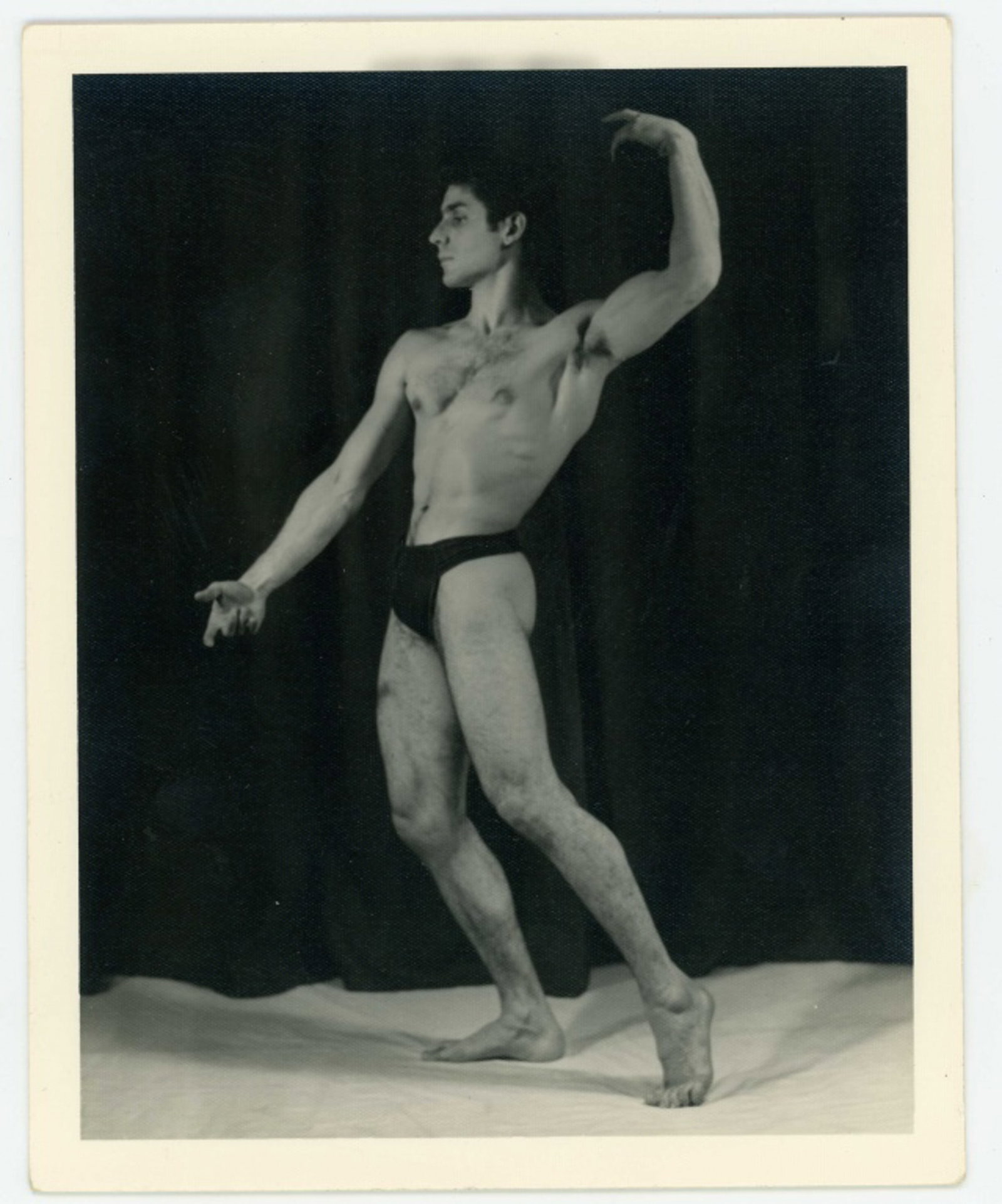 Kris Studio Male Physique Photograph: Vintage original 4" x 5" Chuck Renslow / Kris Studio photograph of model posing in front of a black curtain. KRIS STUDIO stamp and pen written 3. Clear sharp image on double weight textured paper.