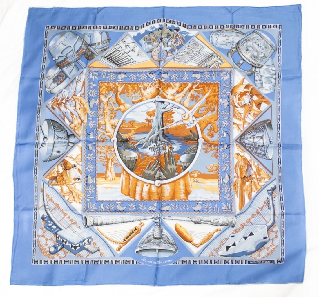 Hermes AU SON DU TAM TAM Silk Scarf: Hermes Au son du Tam-tam silk scarf with light blue background designed by Laurence Bourthoumieux / Toutsy. Hand rolled and stitched edges. Original Made in France label. Very small light spot to righ