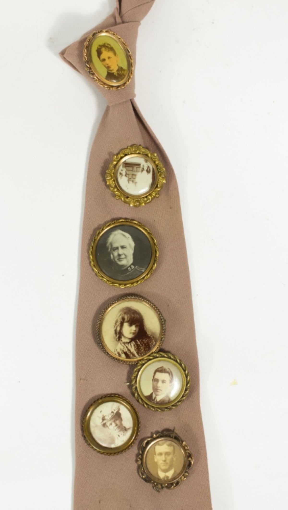 7 Mini-Photo Portrait Pins on a Tie: Antique photo pins of 7 individuals, each framed in a goldtone frame. All photos are good, 1 in an oval frame is hand-colored, and 1 is an out-of-doors photo. Frames vary in detailing and size (1-1/8"