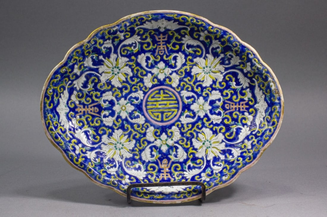 Antique Chinese Cobalt Blue Ground Oval Plate: Circa late 19th century Chinese porcelain oval serving plate. Hand enameled lotus scroll, bat, and character decorations on cobalt blue ground. Unmarked. Good condition with expected gilt wear to to r