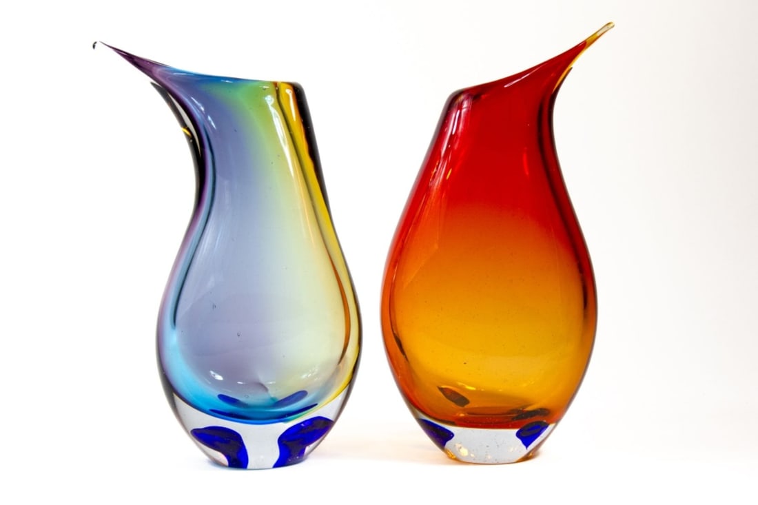 Two Mid Century Murano Glass Vases: Two vintage hand blown Murano glass vases in same shape with large blue glass spots to clear bases. (1) Red to orange amber vase, 11.75" H. (2) Yellow, blue, amethyst vase, 11.5". Both unmarked and in