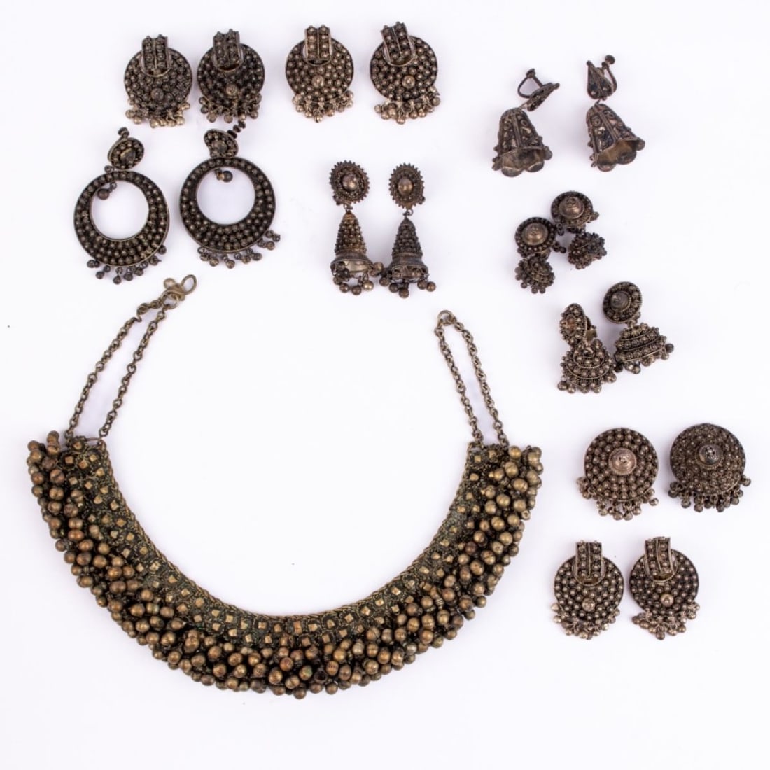 Set of Vintage Indian Metal Jewelry: Set of Vintage Indian metal jewelry. Includes bib necklace and nine pairs of earrings of various forms. Necklace with applied metal bell-form balls, with "woven" construction. All earrings feature gra