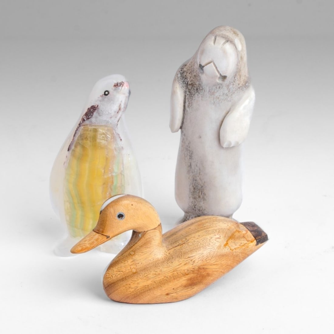 Three Small Inuit Carvings: Three small Inuit carvings. (1): A penguin carved in variegated quartz, with inset bead eye. Damage to mouth and food. Measures 3.25" H approx. (2): A walrus carved from bone, with two drilled holes m