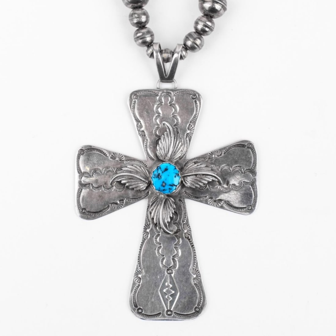 Gary Johnson Navajo Cross Pendant Necklace: Sterling silver cross pendant with stamped designs, applied silver feathers, and center bezel set turquoise stone. Necklace strung with various size silver balls and 1" and 3.75" bone beads. Hook clas