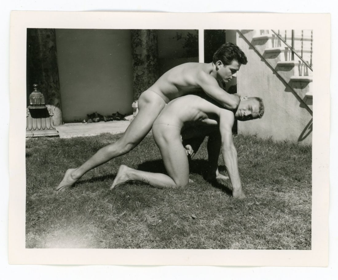 Bob Mizer AMG Nude Male Photo / Dave Wiler: Vintage original AMG photograph of two models wrestling outdoors at Bob Mizer's compound; from the estate of the dark haired model pictured. Pencil written 20 to the back. Good sharp image printed on