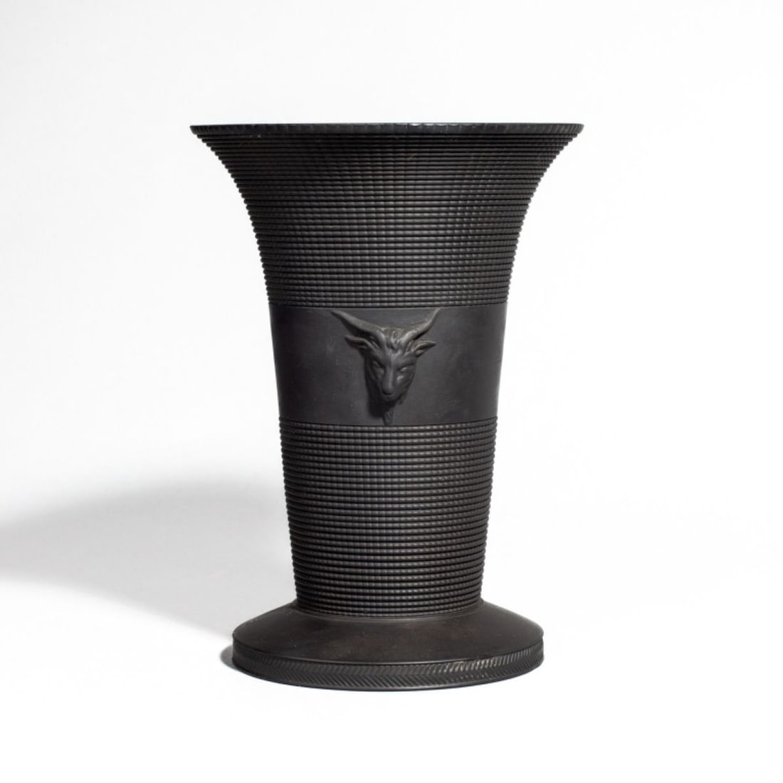 Wedgwood Black Basalt Neoclassical Vase: 19th century Wedgwood black basalt trumpet form vase with ram's heads to each side. Stamped "WEDGWOOD" along with "H" mark to bottom. Very good condition. 7 1/2" H x 3 5/8" lip dia. The Myra O. Karp C
