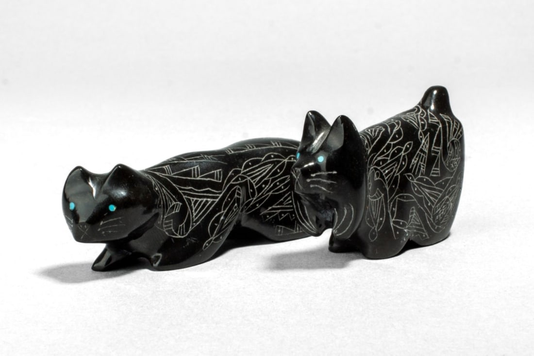 2 Zuni Black Marble Animal Fetishs by C. G.: 2 Zuni Black Marble Animal Fetishs by C. G.. (1): A carved fetish of a mountain lion, with incised stylized patterns to fur coat and turquoise eyes. Signed and dated at base. In very good condition. M