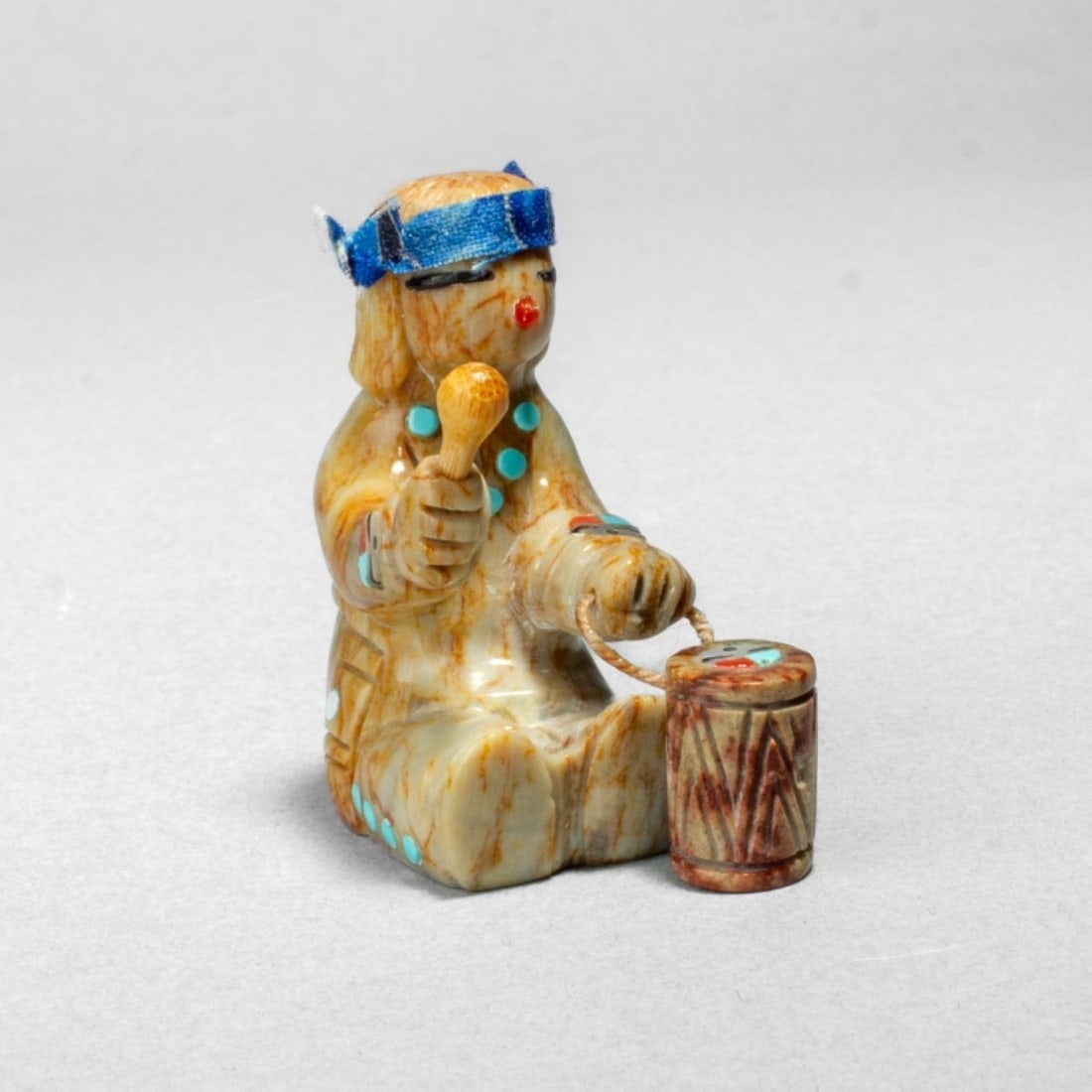 Randy Lucio Drummer Zuni Fetish: Randy Lucio Drummer Zuni Fetish. Carved marble stone of figure holding drum and wood mallet. Figure wears turquoise and red stone garments, with blue cloth bandana. Signed at base. In very good condit