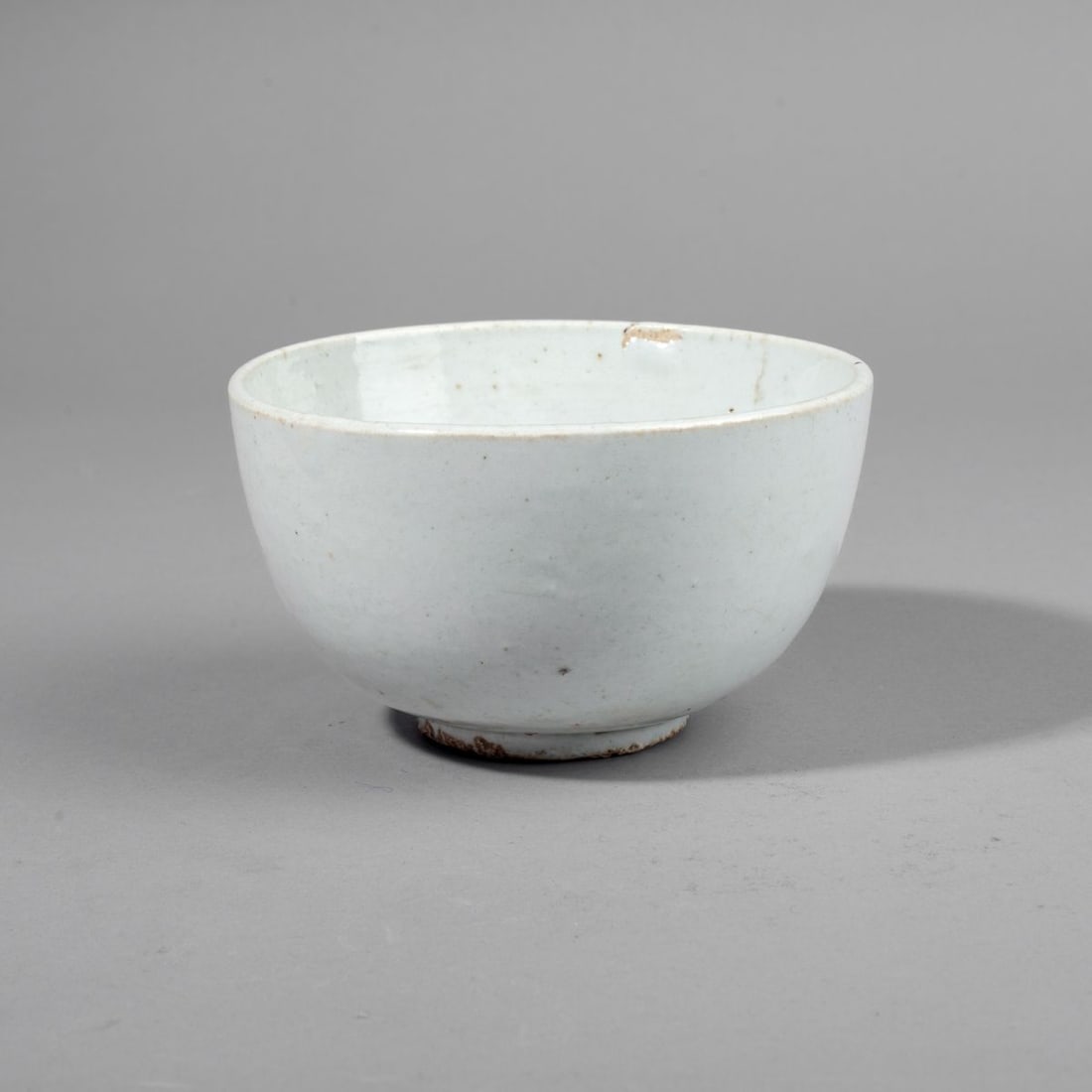 Korean Joseon Porcelain White Ware Bowl: Korean Joseon Porcelain White Ware Bowl. Overall white glaze with gypsum kiln grit to the base. Glazed interior. Some glaze imperfections and light wear. 3.25" H x 5.5" dia.