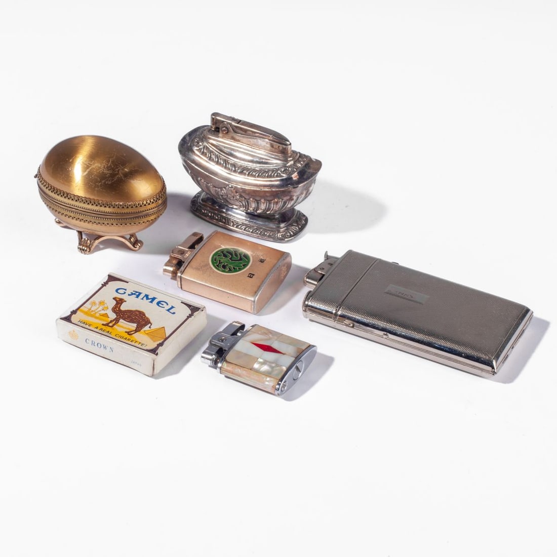 Collection Vintage Novelty Lighters / Evans Egg: (1) Evans brass "egg" hinged lid lighter. 2 1/2" H x 3 1/4". (2) Canary lighter with working music box. 2 1/2" x 1 3/4". (3) Teeco lighter with mother of pearl mosaic. 2" x 1 3/4". (4) Crown "Camel Ci