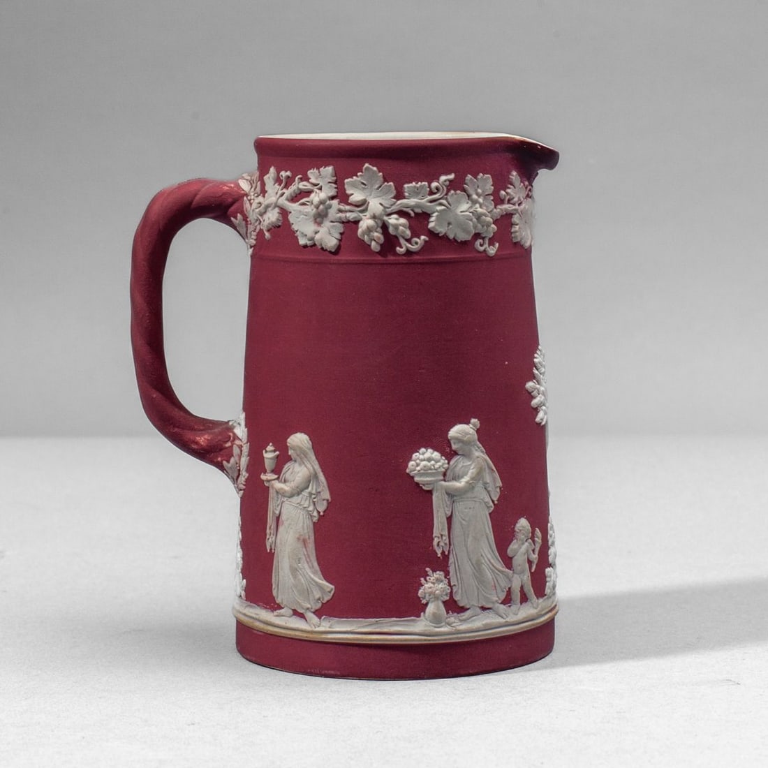 Wedgwood Crimson Dip Jasper Creamer: Late 19th century Wedgwood crimson dip jasperware pitcher. Featuring classical figures bringing sacrifices to an altar. Impressed "WEDGWOOD" and "ENGLAND" marks to underside. Some expected dip stainin