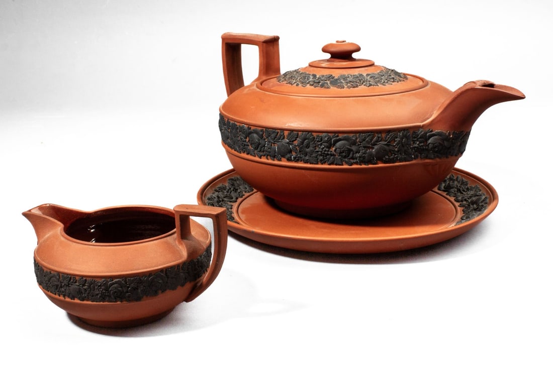 Large Wedgwood Rosso Antico Teapot & Creamer: Large 19th century Wedgwood Rosso Antico teapot. With Egyptian revival handle and variety of flowers and fruits encircling. Impressed "WEDGWOOD" mark to base along with graphite inscription. Restorati