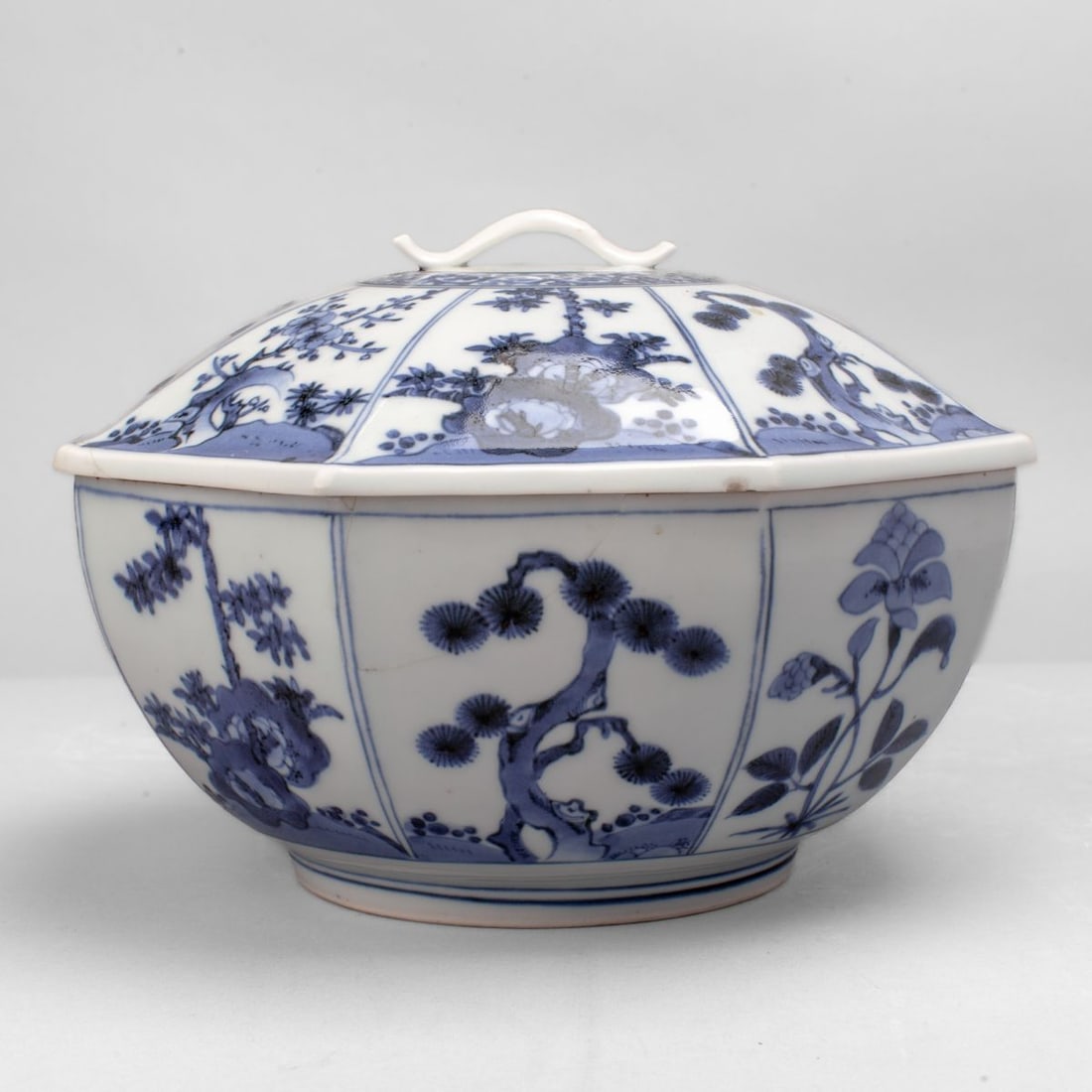 Japanese Hirado Porcelain Octagonal Covered Bowl: A Japanese Hirado ware octagonal lidded bowl. Of pure white porcelain with hand-painted prunus, pine, bamboo and camellia within opposing panels at body and lid, with scrolling vines encircling applie