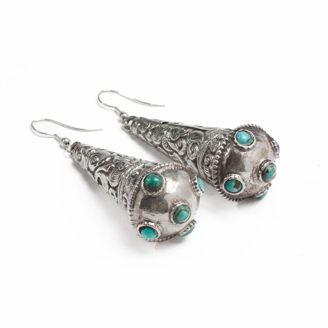 Pair Tibetan Silver & Turquoise Earrings: Pair of Tibetan silver earrings, each of hollow conical form with raised and chased scrolling vines above five inset turquoise stones to each. Some slight rubbing; both in very good condition. UNTESTE