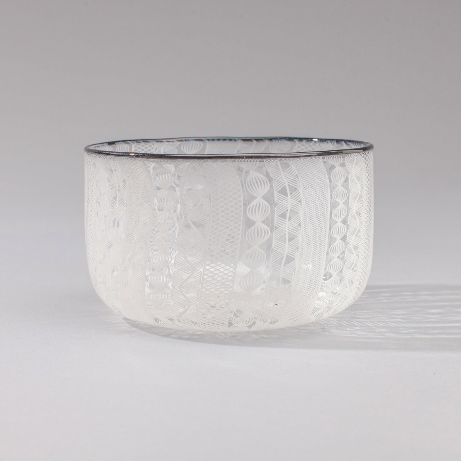 Murano Style Latticino Art Glass Bowl: Murano Style Latticino Art Glass Bowl. Unsigned; probably made at Pilchuck possibly by Checco Ongaro. Black lip wrap and white lace cane work. Measures 3x5". Excellent condition. Collection of