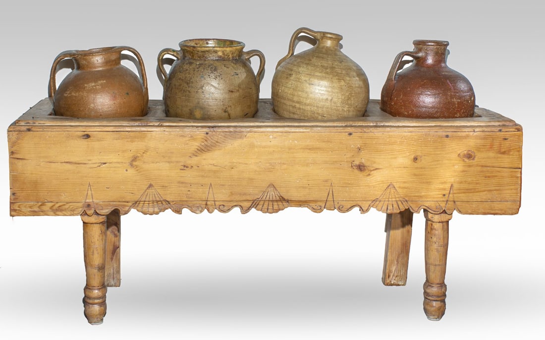 Antique Spanish Folk Jug Storage Wood Bench: 19th century Spanish wood bench of pine wood in tenon-and-mortise and nail construction with four cavities used to hold stoneware water and grain jugs. Carved shell motif to apron. Currently holding f