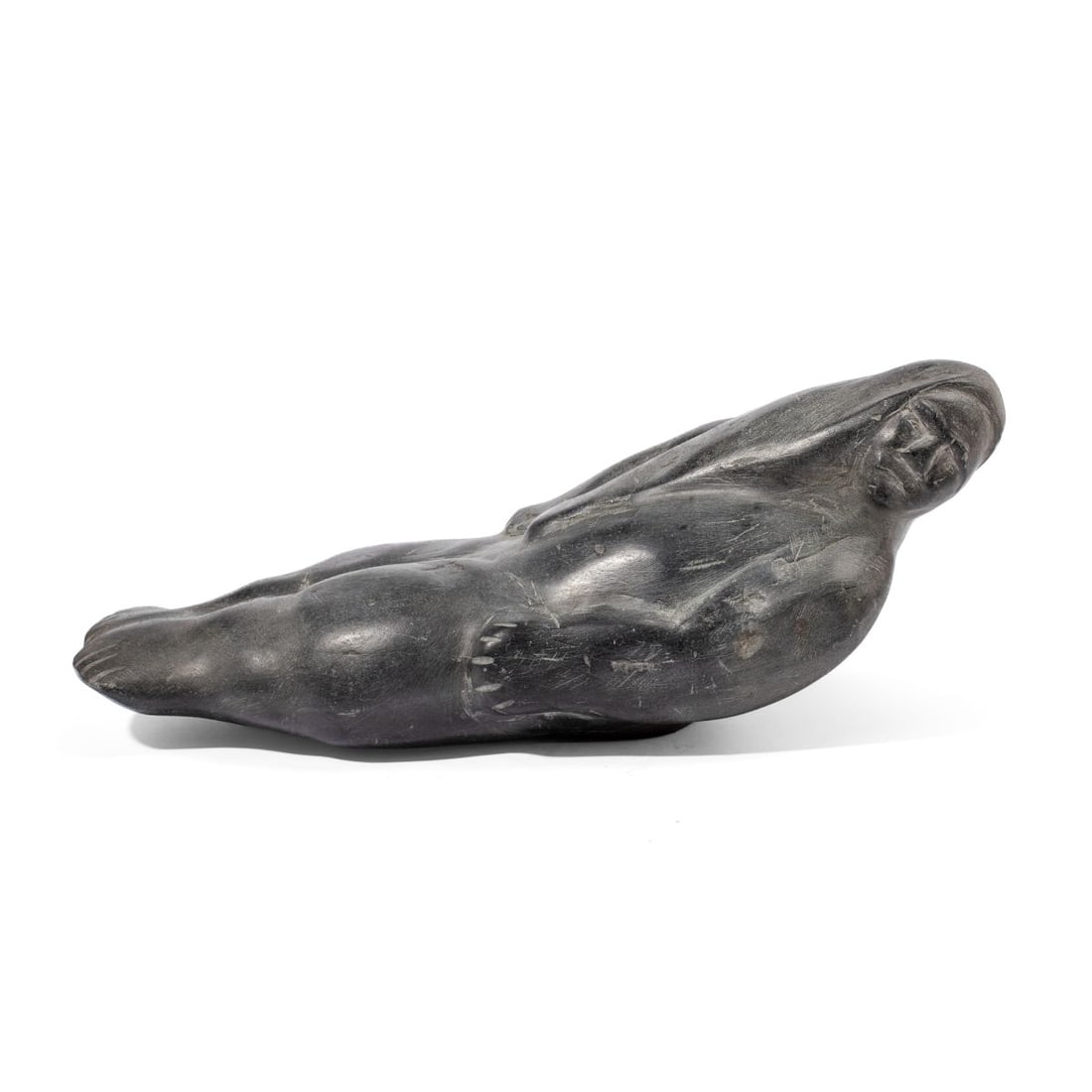 Barnabus Arnasungaaq "Sedna" Stone Sculpture: Inuit soapstone sculpture of Sedna in repose, modeled in dense black stone. Carved by Barnabus Arnasungaaq (1924 - 2017 Baker Lake). Dated 1976. Darkened area to underside from adhesive putty residue,