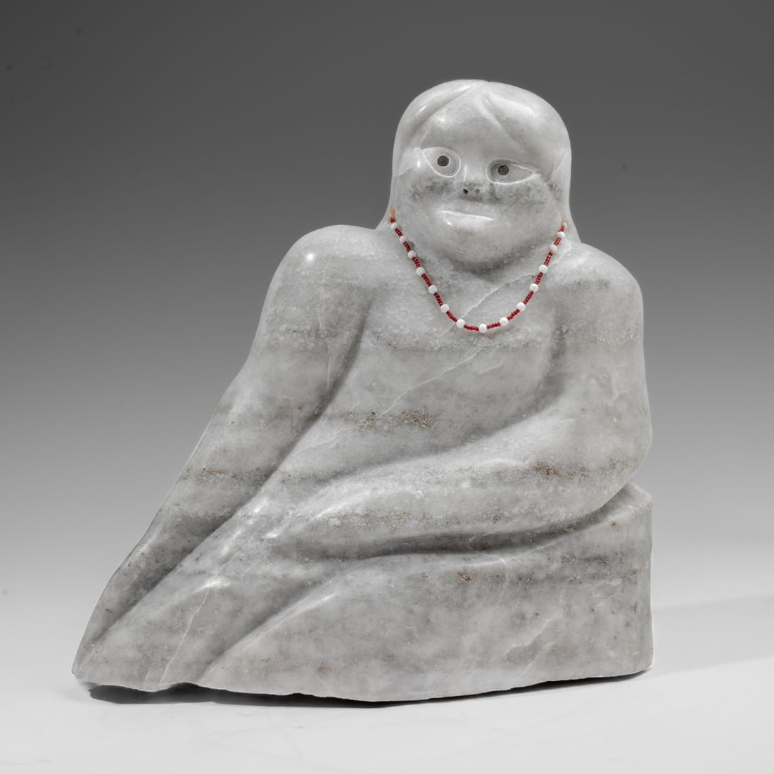 Inuit Quartzite Stone Sculpture of a Woman: Large Inuit carved quartzite sculpture of a reclining woman wearing a beaded necklace. Unsigned. Slight loss to underside corner; in good overall condition. 14" H x 13" L x 7".