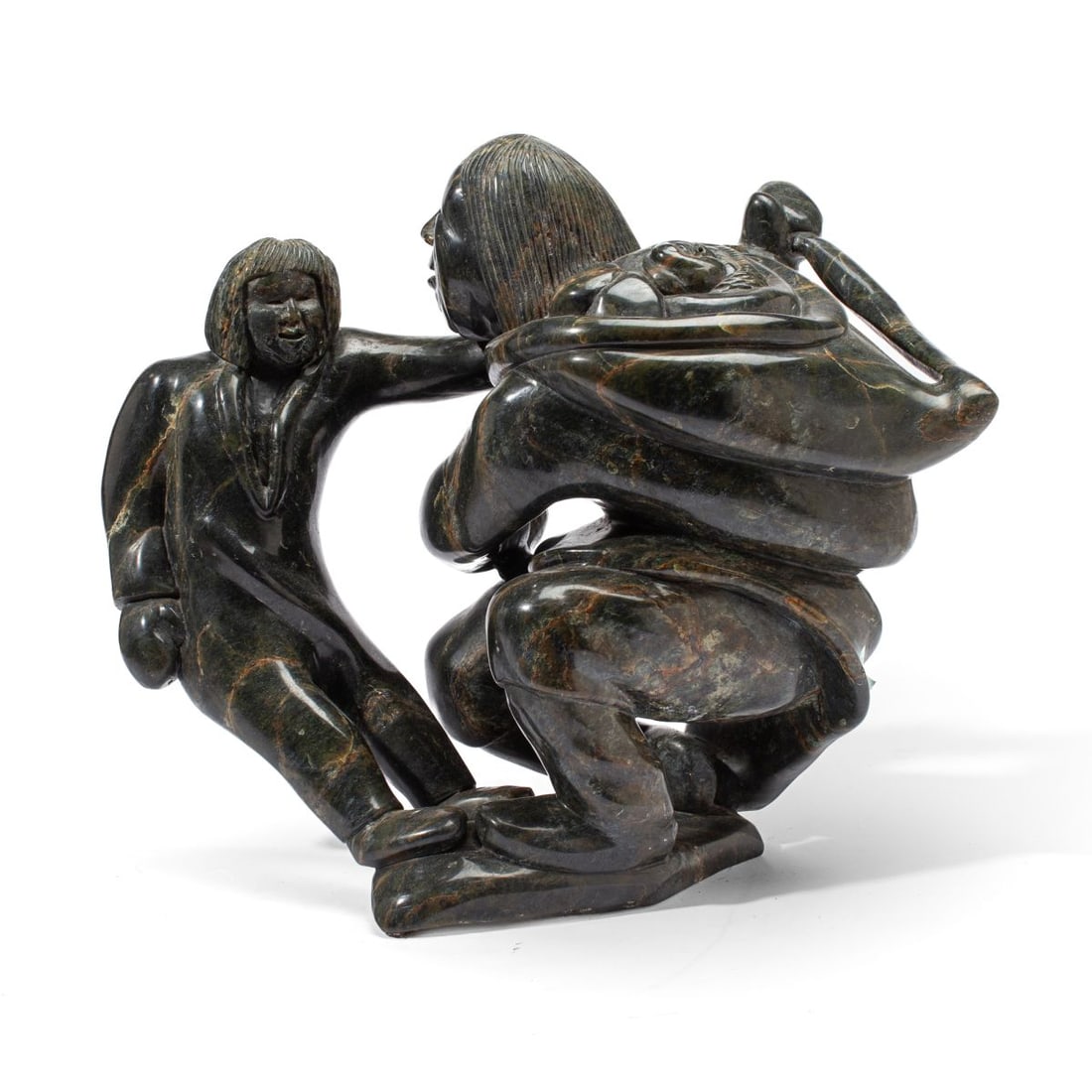 Kiawak Ashoona Mother & Children Stone Sculpture: Kiawak Ashoona (1933 - 2014, Cape Dorset) large carved serpentine stone sculpture of a mother with child tugging at her amauti. Signed in syllabics at base. 1" chip to stone; otherwise in very