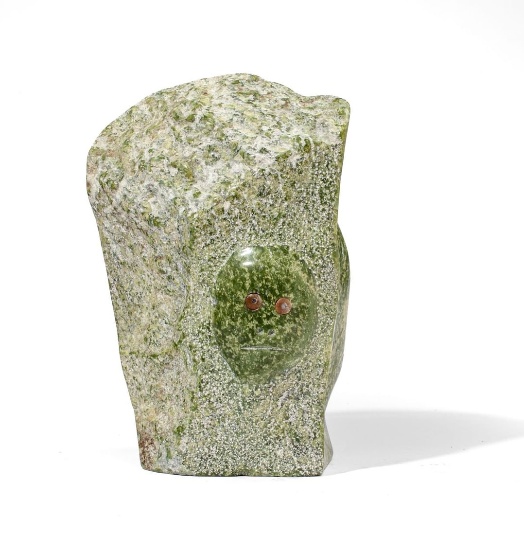 Matiusie Iyaituk "Famine" Green Stone Sculpture: Matiusie Iyaituk (b. 1950, Ivujivik) "Famine" green stone / Alaska jade sculpture depicting face in relief with inlaid stone eyes. Inscribed to base: "Iyaituk comes home empty handed during the 