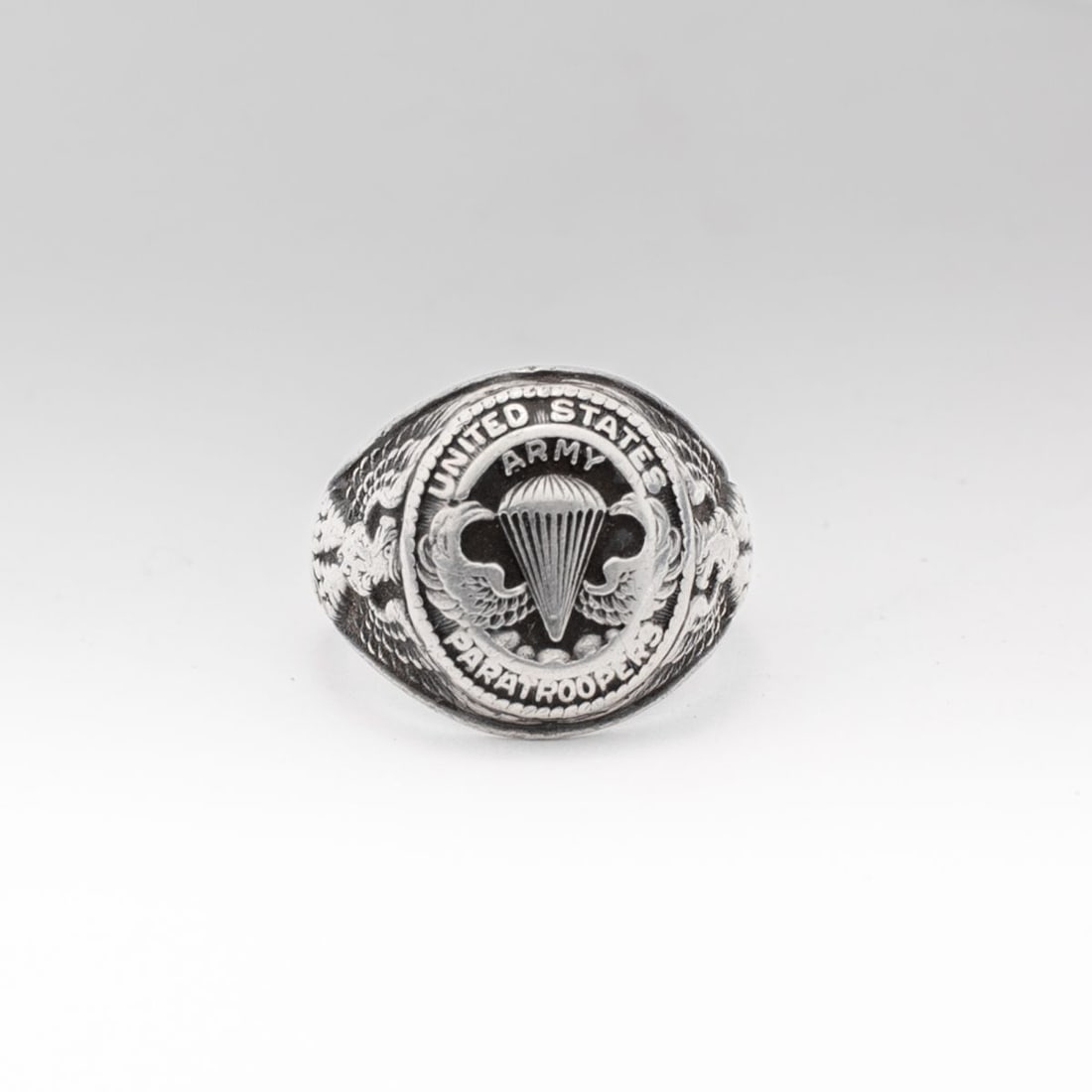 WWII US Army Airborne Paratrooper Sterling Ring: Vintage sterling silver "UNITED STATES ARMY PARATROOPERS" ring with winged parachute to the oval center and eagles to each side. Stamped STERLING to the inside. Good condition with light expected wear