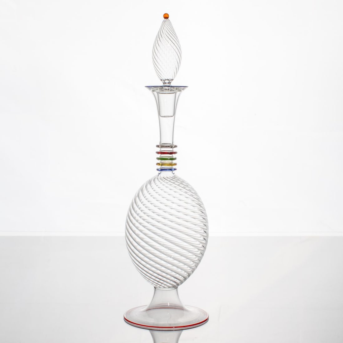 Cesar Toffelo Murano Glass Decanter: Cesar Toffelo (b. 1961 Italy) blown glass decanter. Twisted glass bowl below applied rings of blue, yellow, green, red and clear leading to twist drop-form stopper. Signed at base. In excellent