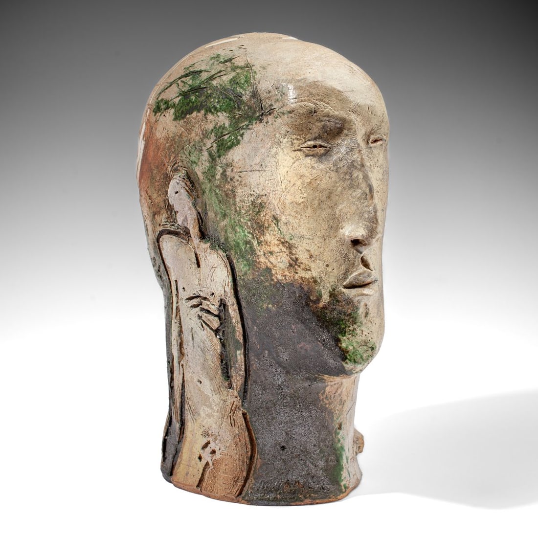Mike Moran (WA) Surrealist Bust Pottery Sculpture: Mike Moran (Washington / Seattle) ceramic sculpture of a bust with male and female figures modeled in relief at opposing sides, with green and grey applied glazes and ceramic inlay. Incised 