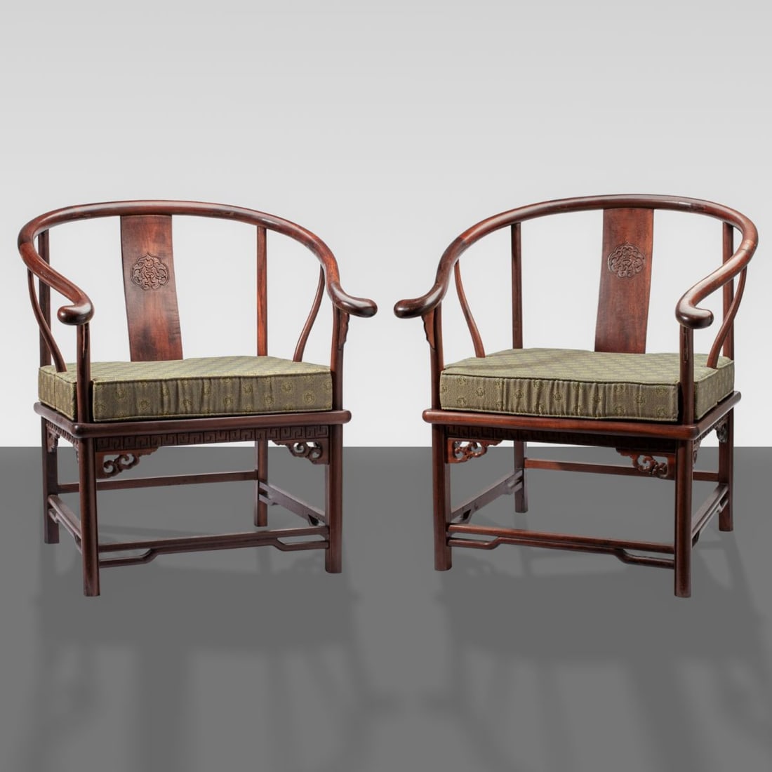 Pair Chinese Rosewood Ming Style Horseshoe Chairs: Pair of Chinese rosewood Ming-style horseshoe back armchairs. Each with carved archaic dragon in relief on backsplat. Adjustable wood paneling to seat. Each chair includes fitted woven silk cushion. S