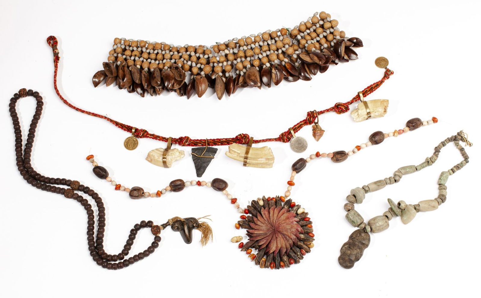 Collection of Hand Made Tribal Jewelry: (1) Pre Columbian style hardstone necklace with carved mask 2.5" pendant. 20" L approx. (2) South American necklace with boar tusk fragments, arrow heads, Chilean coins; all on woven fabric cord. 