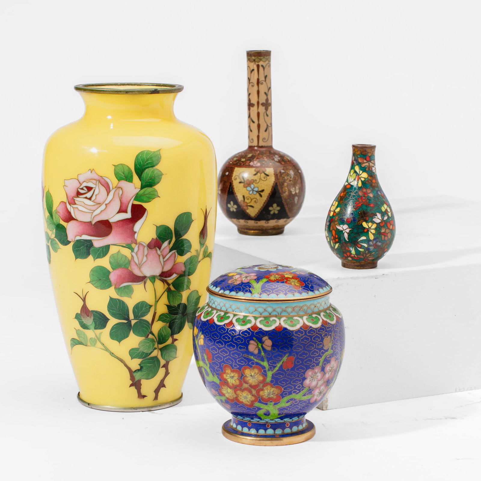 Four Japanese & Chinese Cloisonne Vases: Four Japanese & Chinese cloisonne enamel vases. (1): Japanese vase depicting roses over yellow ground in silver wire. Unmarked. In good condition with only a slight dent at footrim. 7.5" H. (2): Japan