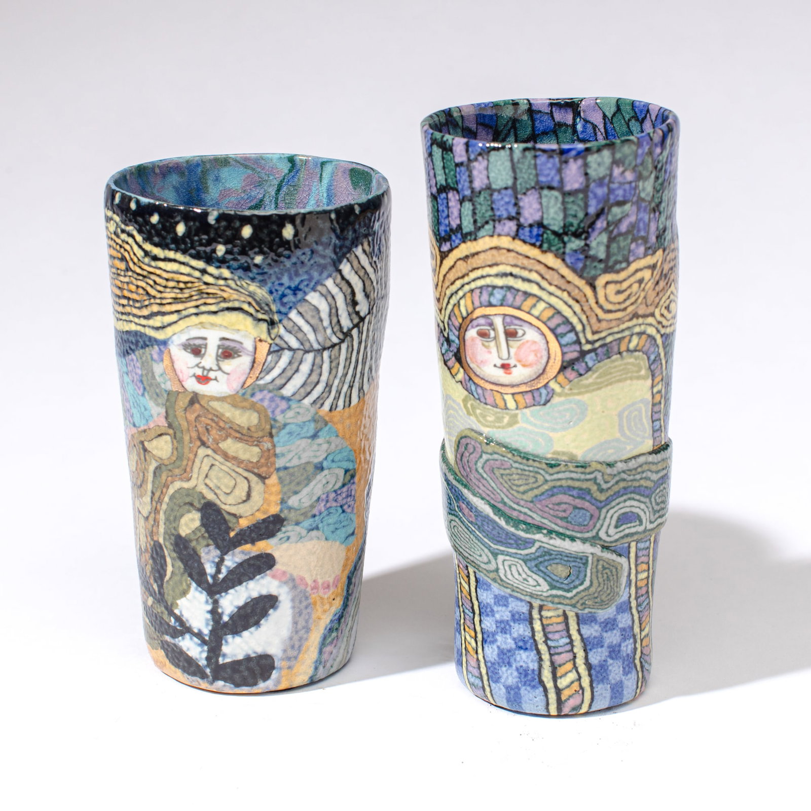 Jane Peiser Pair Millefiori Clay Tumblers: Jane Peiser (1933-2022 North Carolina) Pair Millefiori Clay Tumblers. One hand signed, one stamped. Multi-colored clay mosaic style decoration depicting ethereal beauties against vivid landscapes.