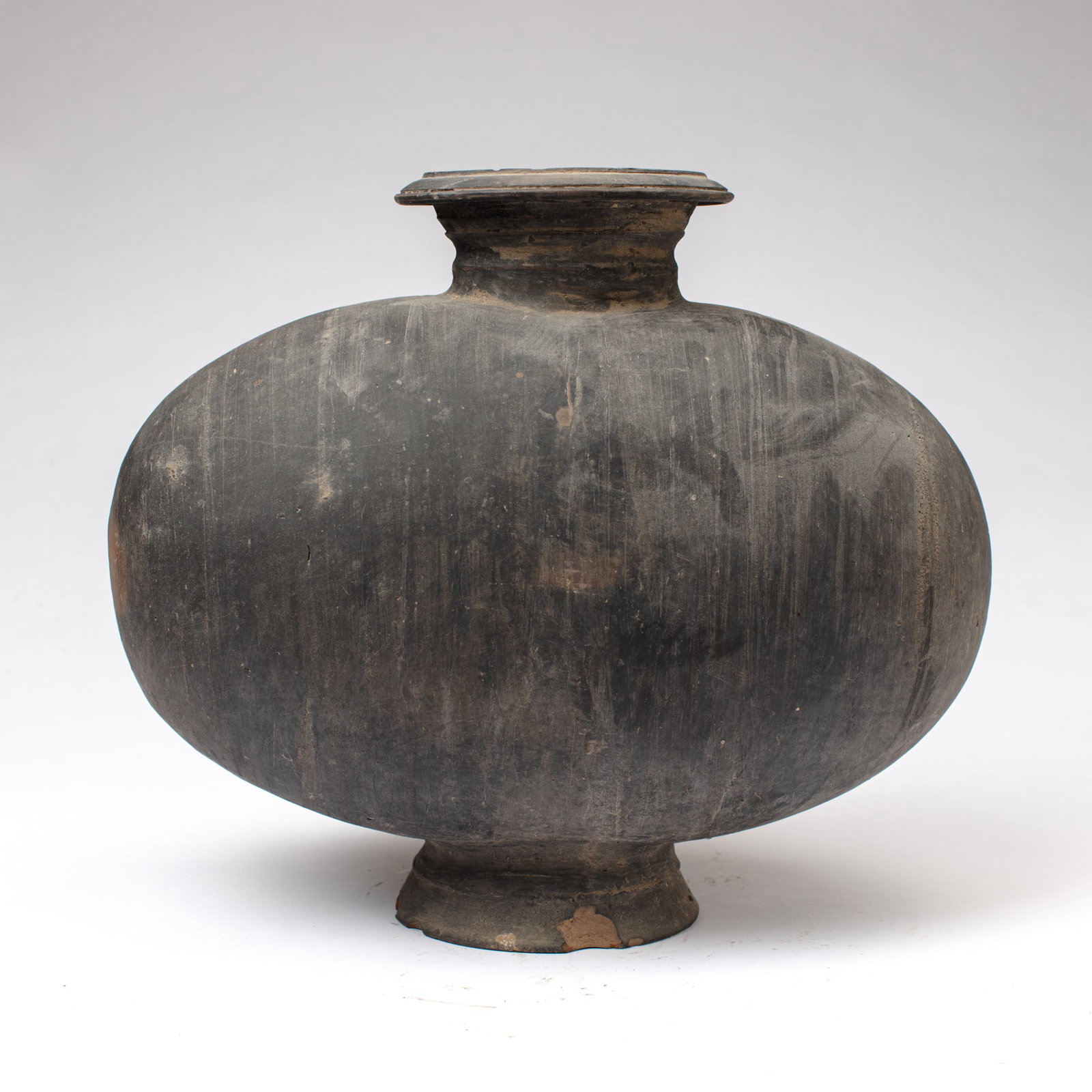 Chinese Western Han Dynasty Pottery Cocoon Jar: Chinese Western Han Dynasty grey pottery cocoon jar in black pottery with faint incised turned lines to body. Losses to base; small chip and some losses to rim; some dirt. 13" H x 14" x 7.5".
