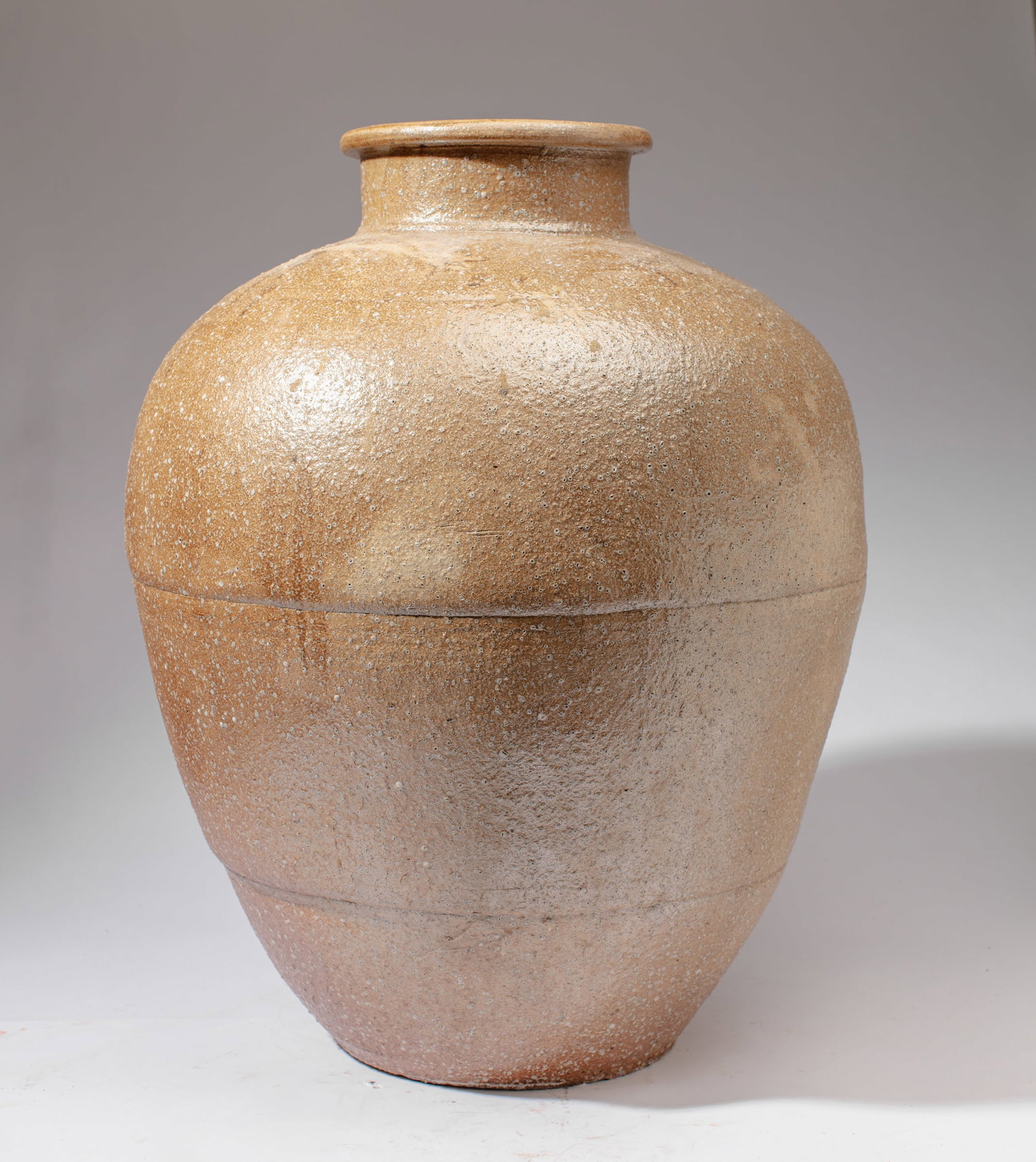Large Japanese Shigaraki Ware Storage Jar: Large Japanese Shigaraki Ware storage jar of broad even form joined in three sections, covered throughout by thin pale ash glaze over buff stoneware body with vitrified crystalline spots interspersed.
