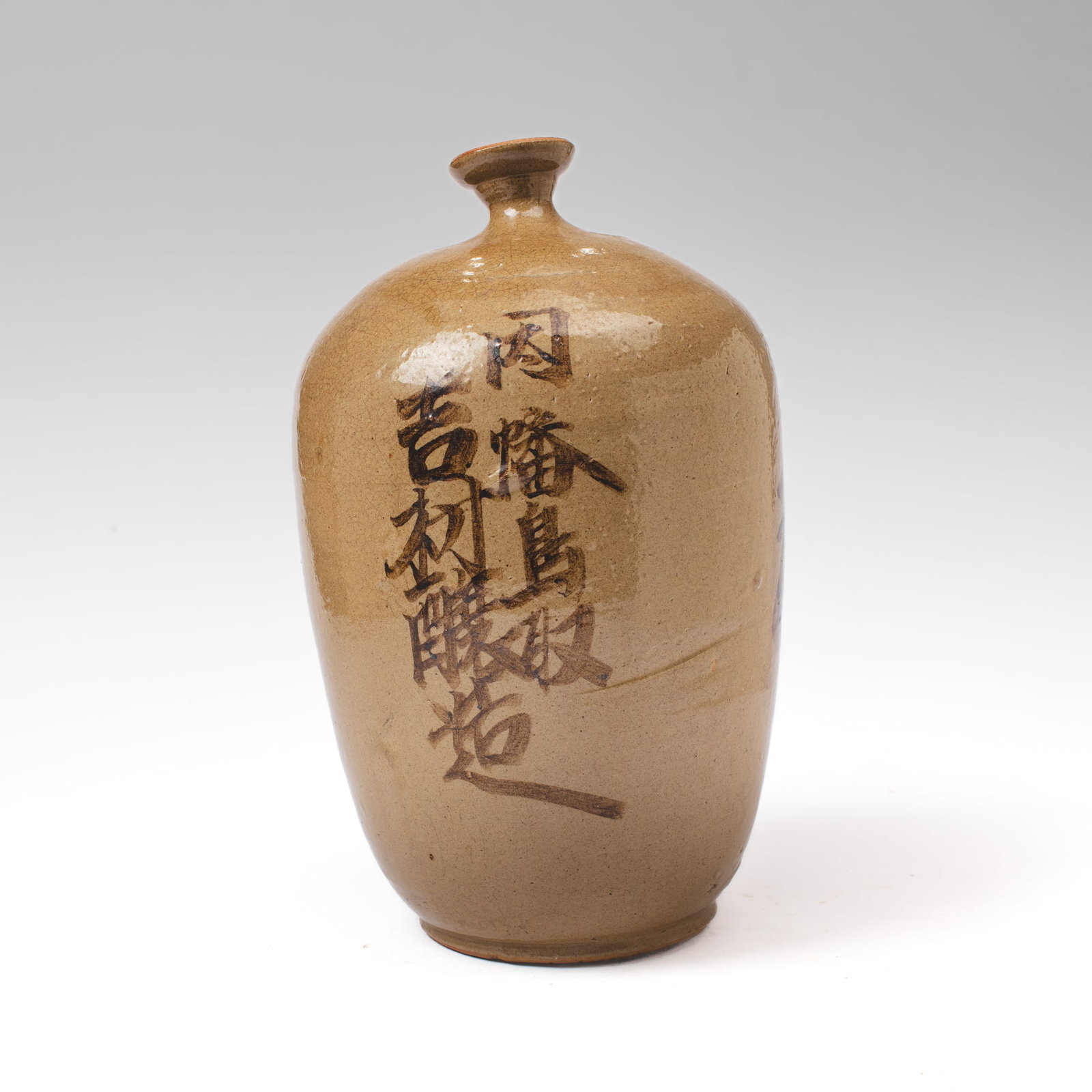 Japanese Kayoi Tokkuri Sake Bottle: Japanese Kayoi Tokkuri sake bottle with calligraphic inscriptions in iron-brown glaze over olive with fine crackle. Losses to surface but presents well overall. 14.5" H x 7.5" D at shoulder.