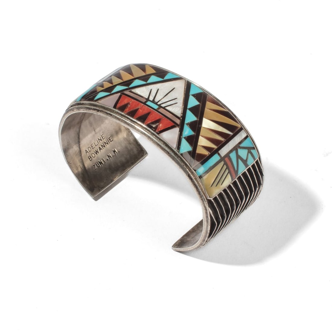 Adeline Bowannie Zuni Silver & Inlay Cuff: Adeline Bowannie Zuni silver cuff bracelet inlaid with coral, jet, turquoise, and mother-of pearl. Soldered wire geometric patterns at each end. Stamped "ANNIE BOWANNIE ZUNI N. M." to interior. In