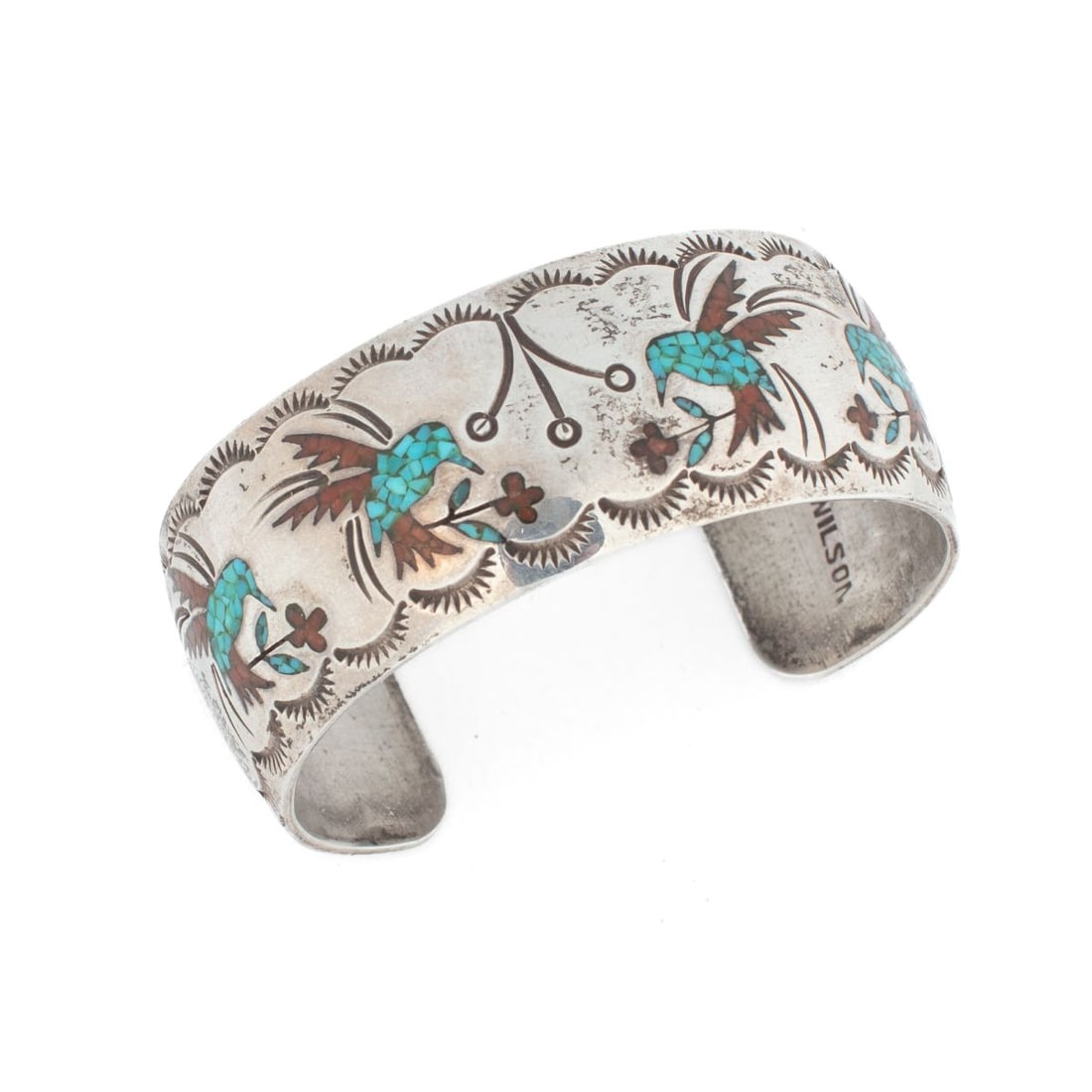 J.J. Wilson Navajo Silver Turquoise & Coral Cuff: Vintage Navajo silver cuff bracelet with coral and turquoise chip-inlaid hummingbird pattern. Stamped "J. J. WILSON" to interior. Very good condition. 1" width. Interior diameter 6" approx. with a