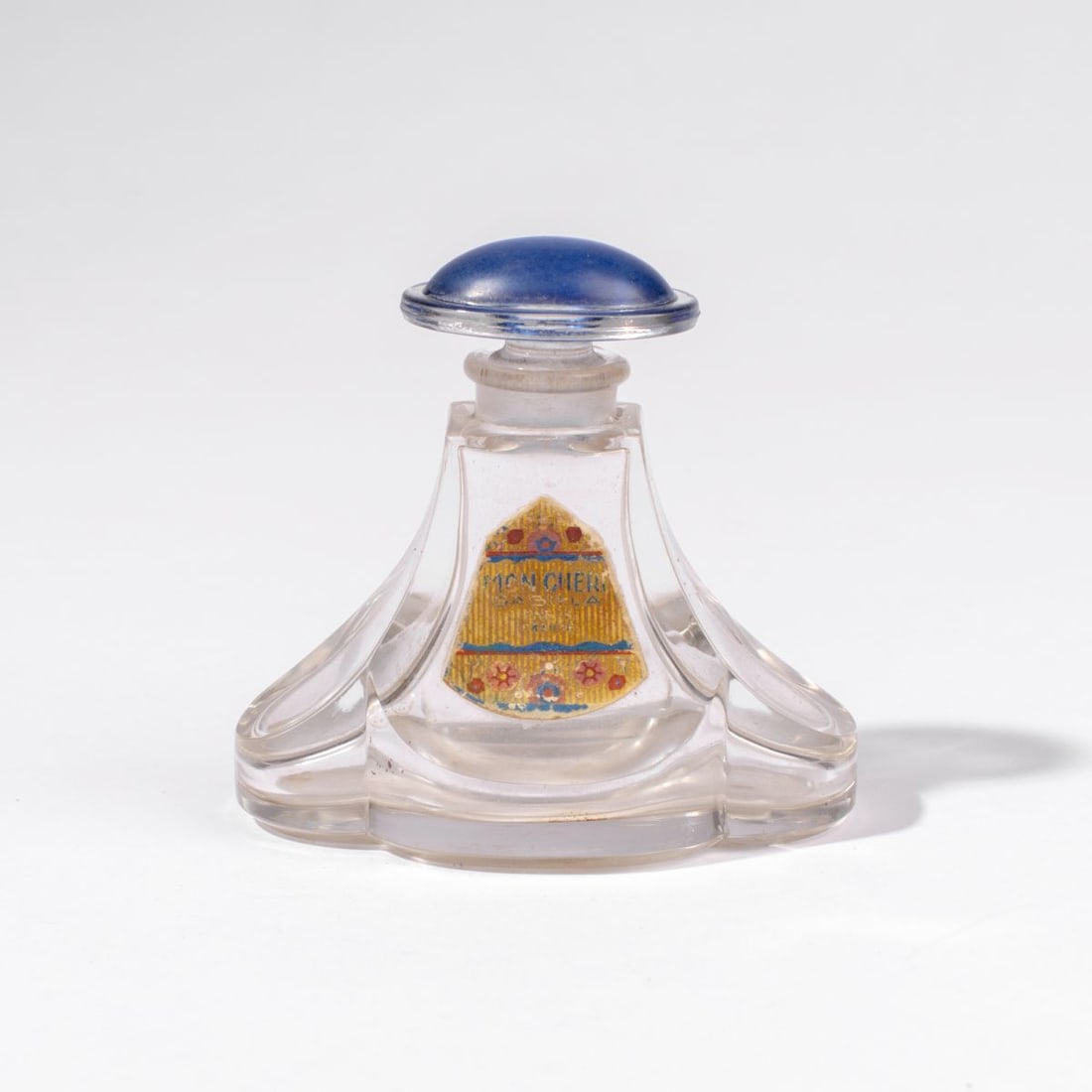 Antique Baccarat Gabilla Mon Cheri Perfume Bottle: Early 20th century Gabilla "Mon Cheri" glass perfume bottle by Baccarat. Stopper with blue enamel top and original paper label to front (some expected age wear). Bottom acid etched with Baccarat logo