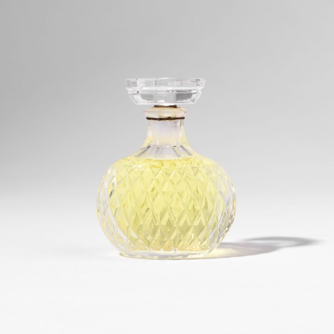 Lalique Nina Ricci Caprica Perfume Bottle: Vintage Nina Ricci "Caprica" 1oz. cut glass perfume bottle by Lalique. Designed by Marc Lalique circa1961. Sealed with perfume by original gold metal wire cord. Acid etched marks to the bottom. 3.5" H