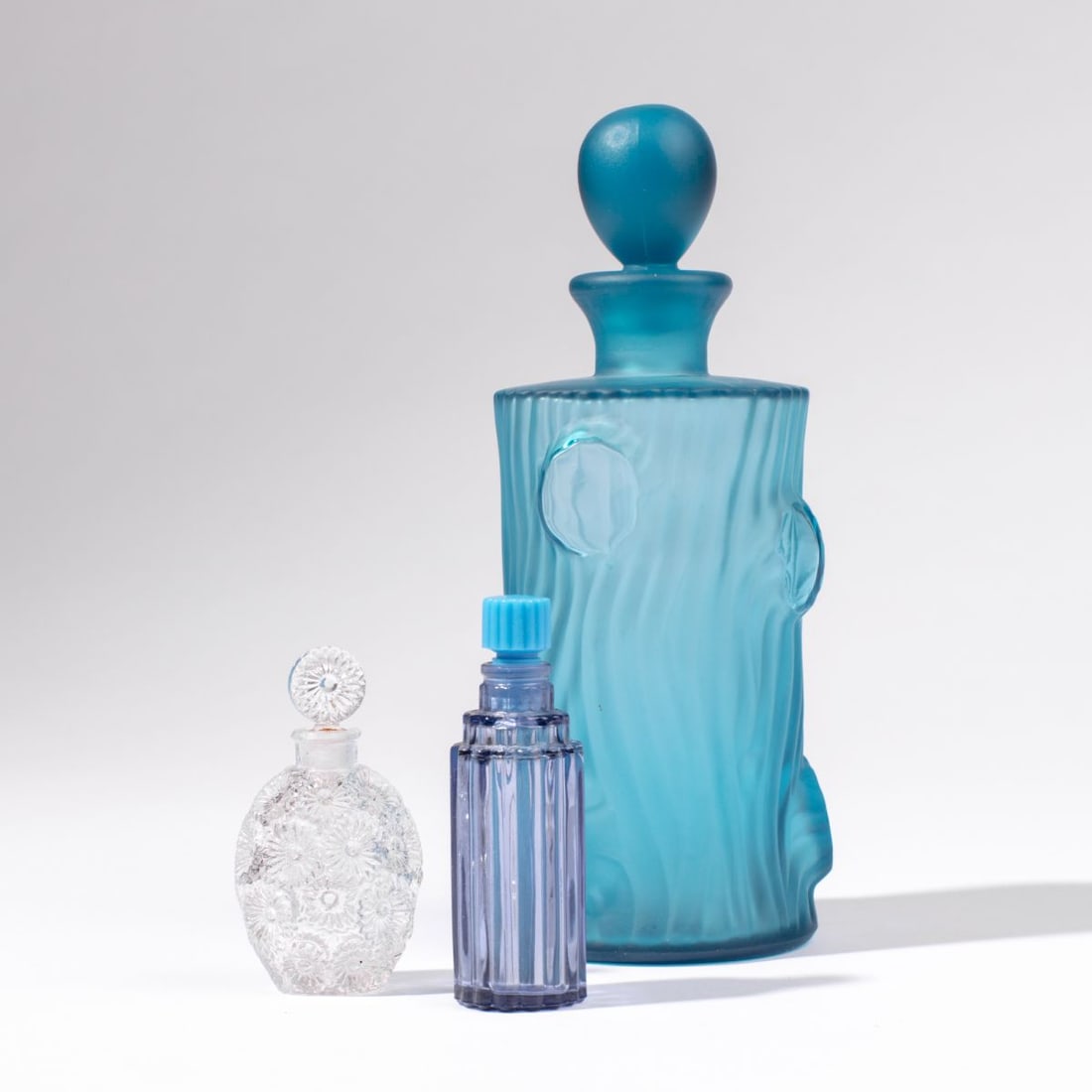Vintage Lalique Perfume Bottles for Worth: Collection of 3 vintage Lalique and French glass perfume bottle. (1) Clear Lalique for Worth glass bottle with impressed floral design. Raised "R LALIQUE FRANCE" mark to bottom. Very tiny flea bite
