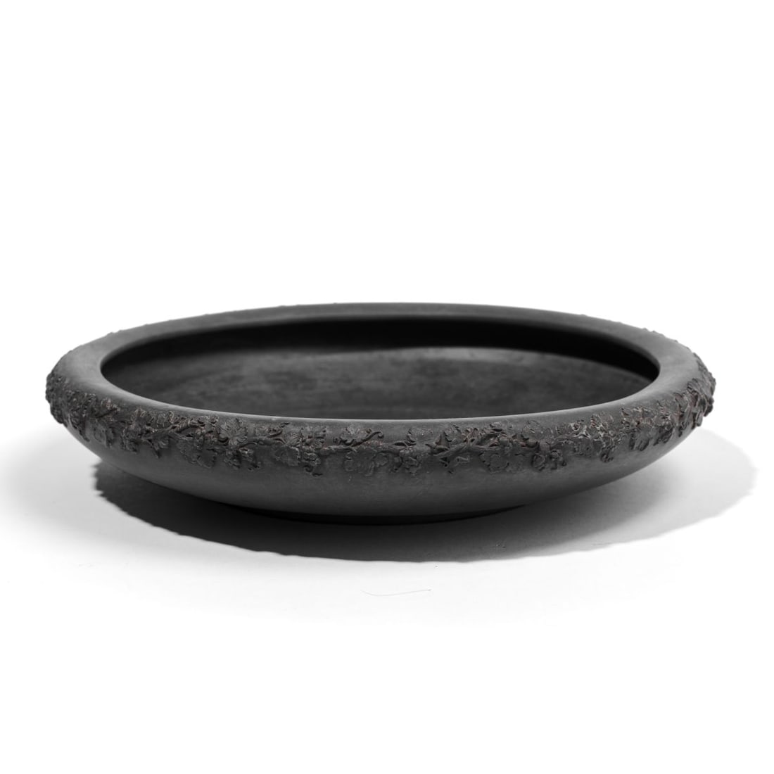 Wedgwood Basalt Grape Pattern Gardenia Bowl: 20th century Wedgwood black basalt gardenia / flower bowl of low wide form with applied grape pattern to shoulder. Impressed "WEDGWOOD" and "MADE IN ENGLAND" marks discernible at underside. 11" D.