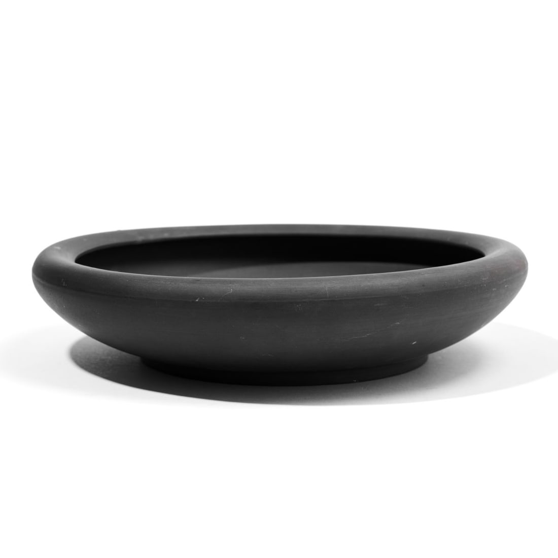 Wedgwood Basalt Gardenia Flower Bowl: 19th century Wedgwood black basalt gardenia / flower bowl of low wide form and inverted rim. Impressed "WEDGWOOD" mark discernible at base. Small pucker to lip; slight expected surface wear. 11" D.