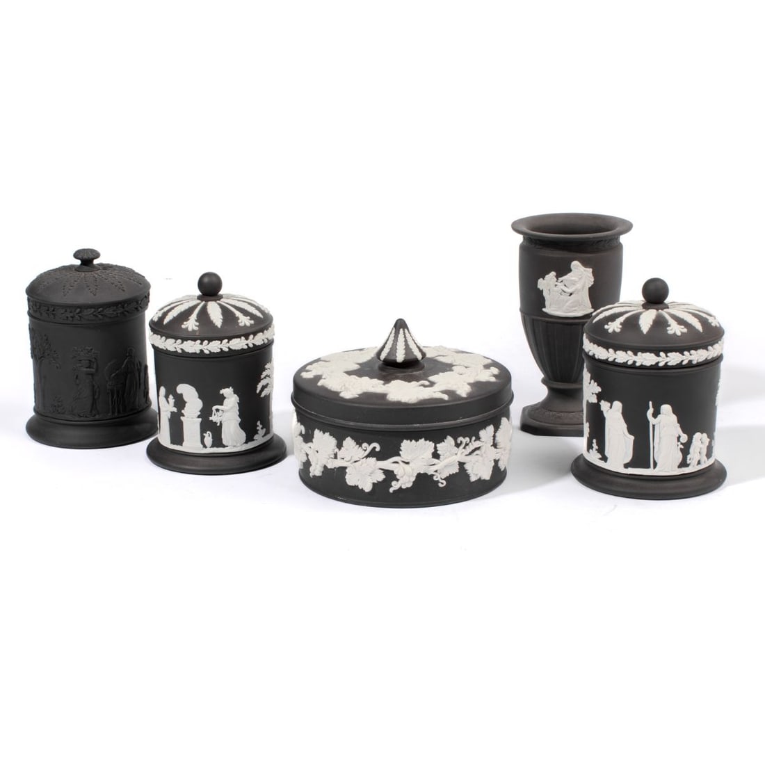 Wedgwood Black Basalt Tea Caddies / Cannister: Five 20th century Wedgwood black basalt articles. (1): Pair of tea caddies having classical figures between laurel trees in white dip below domed lid with radiating acanthus. Impressed marks to unders