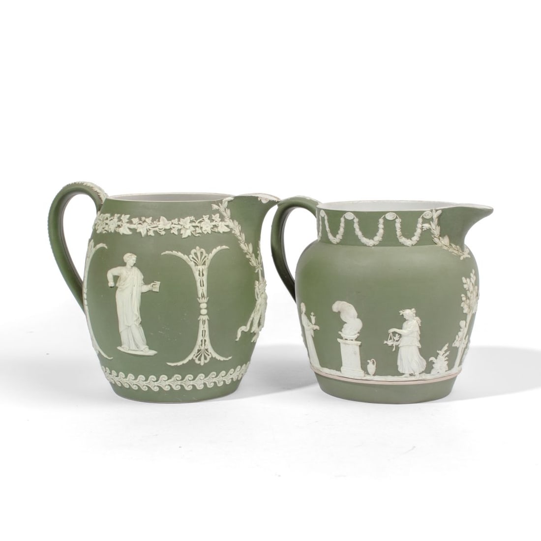 Two Wedgwood Green Dip Jasperware Jugs: Two early 20th century Wedgwood green dip jasperware jugs. (1): Cider jug having masked woman or actress and man holding book below grapes and corinthian border; wreath of victory and laurel at spout.
