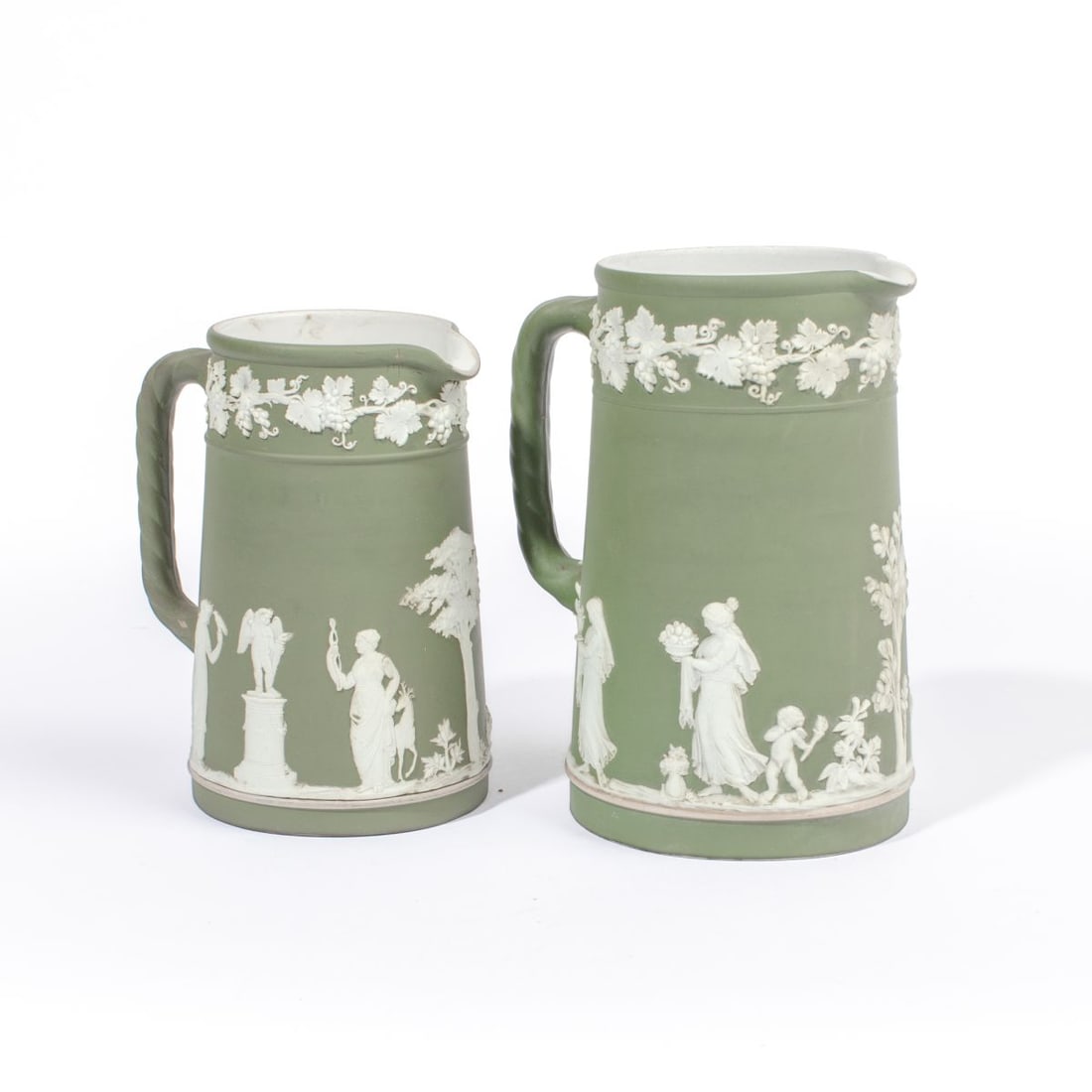 Two Wedgwood Green Dip Jasperware Pitchers: Two early 20th century Wedgwood green dip jasperware pitchers. (1): Maidens offering sacrifice below grape border. Impressed "WEDGWOOD" and "ENGLAND" marks to underside. In very good condition. 6.25" 
