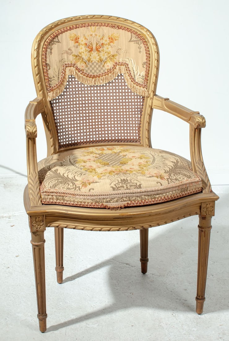Antique Louis XVI Style Cane Armchair: Antique French Louis XVI style armchair with woven cane back and seat. Floral silk (?) tapestry tie on seat cushion and partial chair back fringed pad. Gold painted frame in good sturdy condition; som
