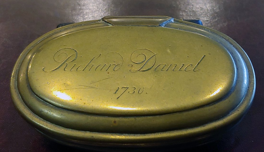 Colonial America British 1730 Inscribed Tobacco Box: Super appealing personal item. An oval brass tobacco box or large snuff box with a hinged lid engraved "Richard Daniel 1730". Approx 4 inches long. This is nearly 300 years old, from era of the reign 