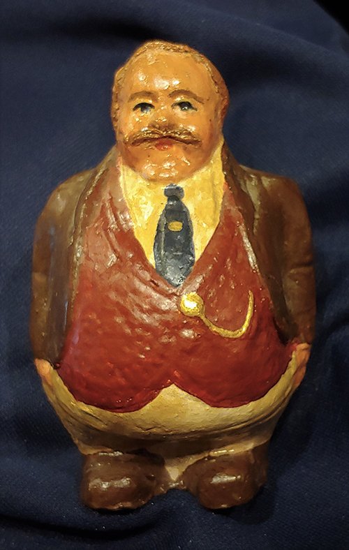 William Howard Taft ? Piggy Bank: I've never seen another. It is an early 1900s molded clay or plaster coin bank with a large coin slot in the top of the mans back. I am quite confident it is meant to resemble President Taft. Quite po