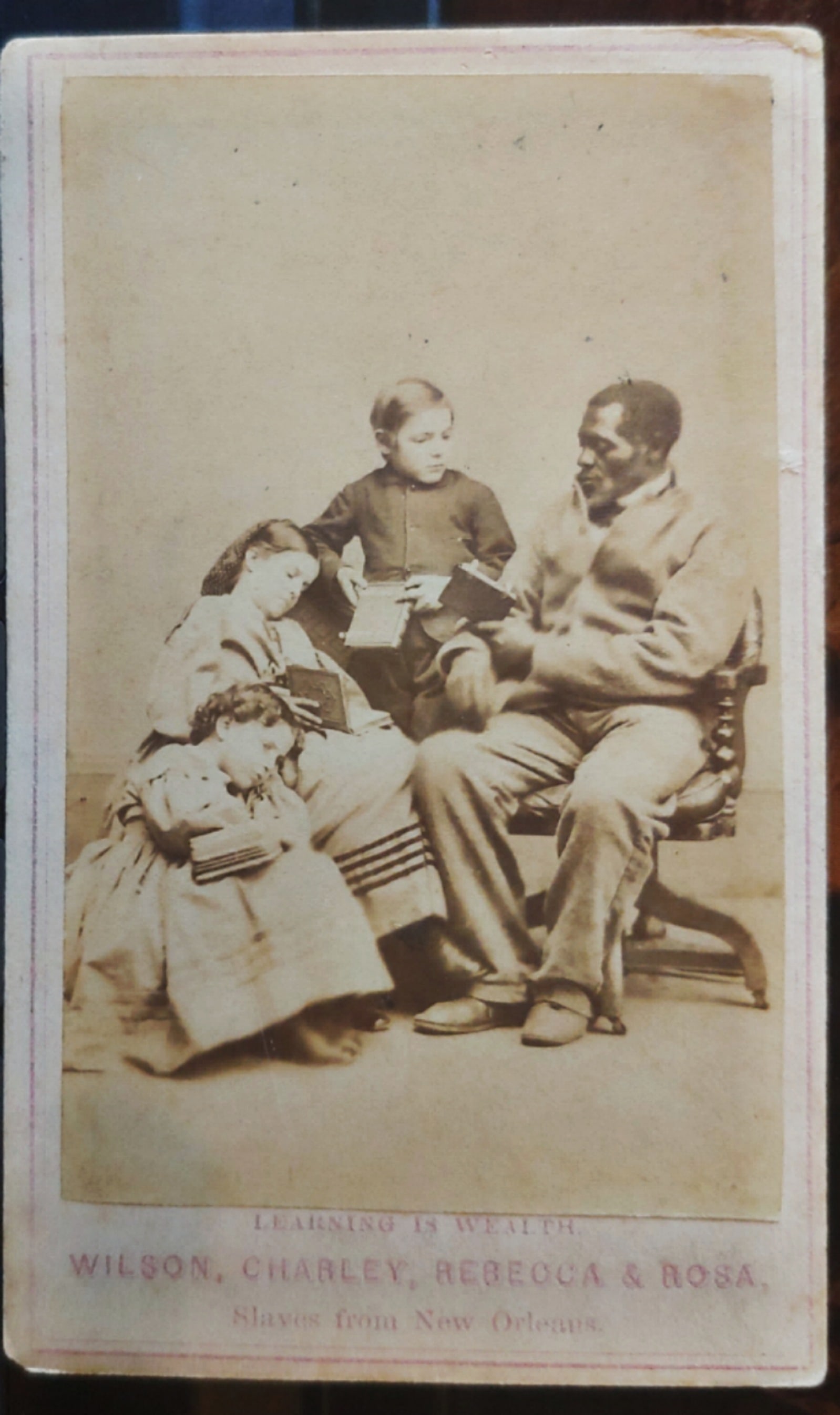 CDV photo of Wilson chin the Branded slave reading to slave children.: In December of 1863, eight former slaves were brought north from New Orleans, sponsored by the American Missionary Association and the National Freedman’s Relief Association. They were taken to phot